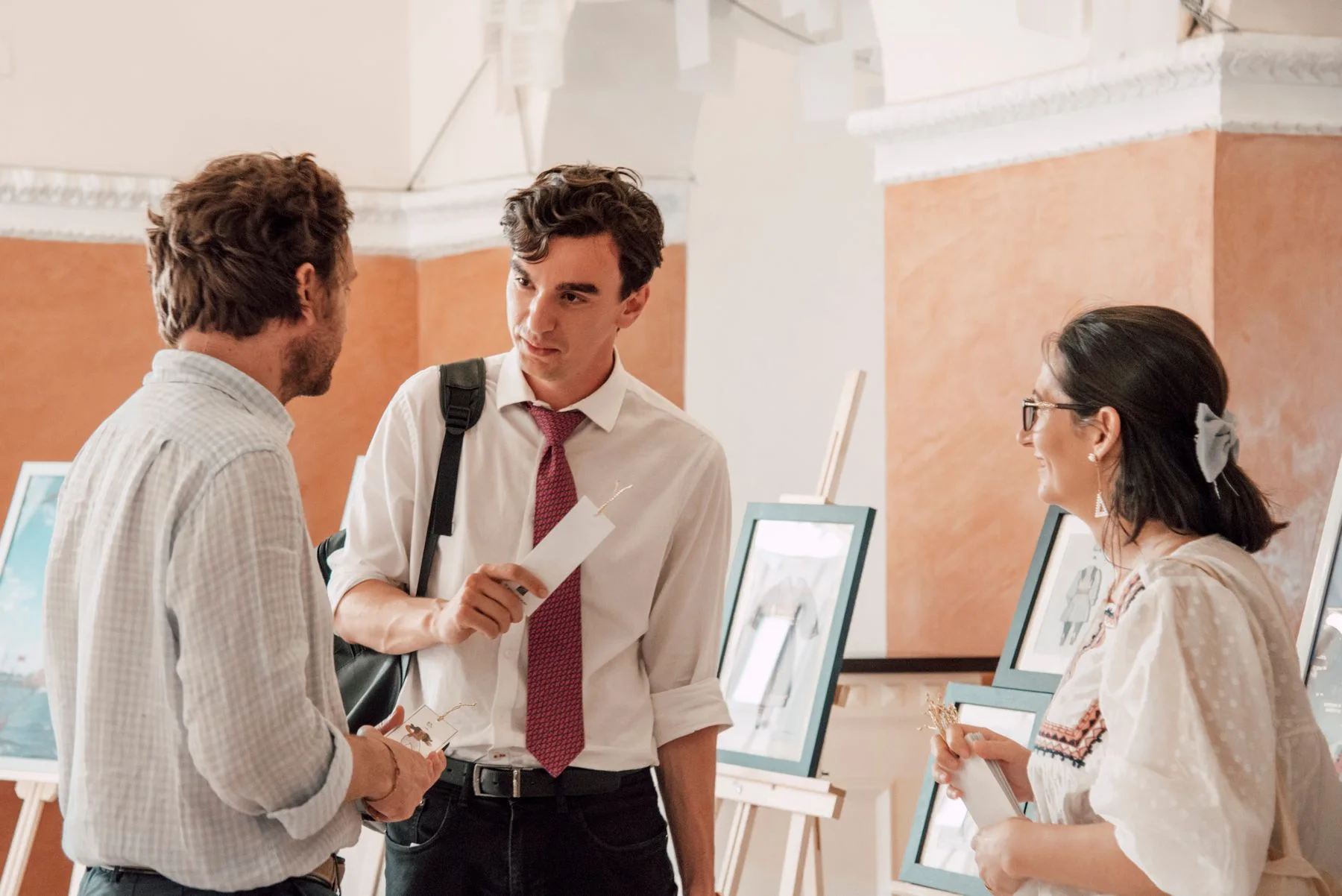 Three people in conversation at an art exhibition